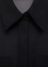 Mono largo negro de tejido fluido semitransparente, con cuello camisero, cierre frontal de botones ocultos, mangas largas con puños abotonados y diseño recto.