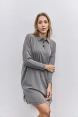 Vestido corto de tejido acanalado en color gris, con cuello polo, cierre frontal de botones y mangas largas con caída de hombros.