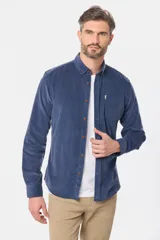 Camisa de pana fina en color verde oscuro, de manga larga con puños arremangados, cuello camisero con botones y un bolsillo aplicado en el pecho con pequeña etiqueta decorativa.