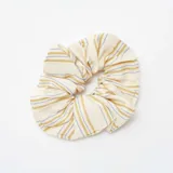 Coletero de tela de algodón color crudo con rayas horizontales doradas y celestes.