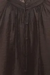 Blusa de cuello subido y manga larga abullonada con puños ajustados. Presenta un diseño semitransparente con textura arrugada y cierre frontal con botones a tono.