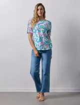 Remera de algodón estampado con diseño paisley en tonos celeste, rosa y amarillo. Tiene cuello redondo y mangas cortas con detalle de entrelazado y aberturas en los hombros.
