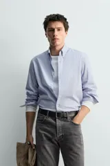 Camisa de corte relajado confeccionada en tejido de algodón con estampado de cuadros pequeños. Presenta cuello abotonado, cierre frontal con botones y manga larga con puños abotonados.