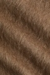 Buzo de punto marrón, con textura suave y peluda, escote redondo y hombros caídos. Presenta remates acanalados en cuello, puños y bajo.