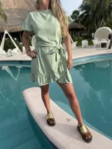 Vestido corto blanco de lino con corte evasé, mangas cortas con volados y cinto del mismo material.