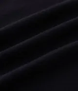 Remera negra de algodón con cuello redondo y mangas cortas. Presenta un estampado frontal con la frase "Divine Spark" y un estampado grande en la espalda de un ángel con halo y rayos celestes.