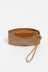 Monedero de cuero vacuno color tostado con cierre superior y correa de muñeca integrada. Presenta el logo metálico de la marca en la parte frontal.