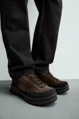 Zapatilla de cordones con parte superior de piel con acabado serraje, horma redonda, suela con volumen y piso track.