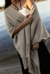 Ruana de lana merino en color tostado, con diseño de punto texturizado y terminación de flecos en el ruedo.
