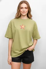 Remera de algodón color verde oliva, con cuello redondo y manga corta. Presenta un estampado central de una estrella de mar en tonos rosados y amarillos.