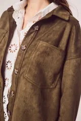 Sobrecamisa de gamuza sintética en color marrón chocolate, con corte oversize, cuello camisero, cierre frontal con botones y bolsillos frontales tipo parche.