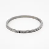Pulsera rígida plateada de acero con cristales incrustados de circonia cúbica.