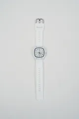 Reloj analógico con caja cuadrada blanca y correa de silicona blanca. La esfera es blanca con números negros y manecillas negras.