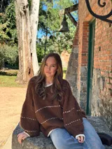 Buzo de tejido de punto en color marrón chocolate, con diseño oversize, cuello redondo y mangas largas abullonadas. Presenta detalles de líneas horizontales en color crudo y terminaciones en contraste en cuello, puños y ruedo.