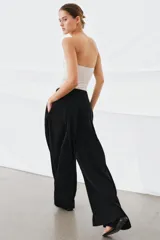 Pantalón de tiro medio de la ZW Collection, color negro, con diseño de pierna ancha (wide leg) y detalle de pliegues en la parte delantera. Cuenta con bolsillos laterales ocultos y cierre frontal con cremallera, botón y ganchos metálicos.