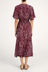 Vestido largo con estampado animal print abstracto en tonos bordó y rosado. Presenta escote en V, mangas cortas con volados y cintura elástica fruncida.