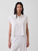 Camisa de lino blanca de manga corta, con cuello camisero, cierre frontal de botones y corte corto.