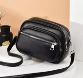 Bandolera negra con tres compartimentos con cierre plateado y correa larga regulable.