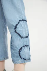 Pantalón de jean celeste con estampado tye dye azul oscuro en los laterales.