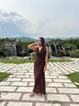 Vestido largo de microtul color marrón, con escote buche y cuello halter regulable. Presenta un diseño ajustado al cuerpo con forro interno corto.