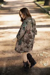 Vestido corto de lino con estampado floral en tonos tierra, verde y marrón. Presenta cuello redondo, mangas tres cuartos con volumen y silueta holgada.