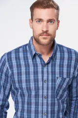 Camisa de manga larga con estampado de cuadros en tonos azules, cuello clásico, cierre frontal con botones y bolsillo en el pecho.