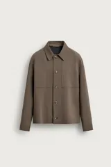 Sobrecamisa negra de corte boxy fit, confeccionada en tejido compacto. Cuenta con cuello solapa, manga larga con puños abotonados, bolsillos de parche en el pecho y cierre frontal con botones.