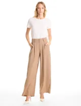 Pantalón tipo palazzo de corte ancho y fluido, confeccionado en tejido sastrero. Presenta tiro alto con doble abotonadura frontal, pinzas decorativas y cintura elástica en la parte posterior. Incluye bolsillos laterales funcionales.