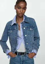 Chaqueta vaquera de corte ajustado y diseño corto, confeccionada en tejido de algodón estilo denim. Cuenta con cuello camisero de solapa, cierre frontal de botones metálicos, bolsillos de parche con solapa en el pecho y manga larga con puños abotonados.