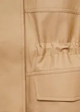 Chaleco oversize color beige, sin mangas, con cuello de solapa, cuatro bolsillos de parche con solapa en la parte delantera, fruncido elástico en la cintura y cierre frontal con botones.