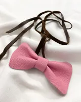 Gargantilla de cuero rosa con forma de moño y tira de cuero marrón para atar.