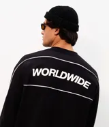 Remera de manga larga Blue Steel, color negro, con diseño de cuello redondo y corte relajado. Presenta un estampado frontal con la palabra 'WORLDWIDE' en letras blancas y detalles de líneas horizontales en contraste.