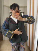 Chaqueta gris de paño de lana con detalles de crochet artesanal en varios colores, cuello solapa y corte oversize.