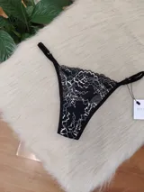 Microtanga de encaje con diseño floral bitono en negro y blanco, con laterales finos ajustables.