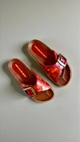 Sandalias de cuero modelo Kiri de la línea Ottenta, color rojo con diseño pintado a mano, una tira ancha con hebilla metálica grande y plantilla anatómica.