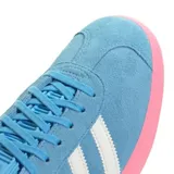 Championes Adidas modelo Gazelle, edición especial Inter Miami CF. Confeccionados en gamuza color celeste con las icónicas tres tiras laterales en blanco y suela de goma en color rosado. Presenta el nombre Gazelle en letras rosadas en el lateral y detalle en blanco en el talón.