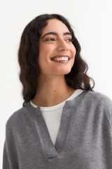 Sweater de tejido de punto color azul marino, con cuello abierto tipo polo y tajos laterales en el ruedo. Presenta mangas largas con puños acanalados y un corte holgado.