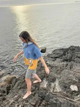 Poncho corto azul con franja horizontal amarilla y bolsillo estampado con motivos florales.