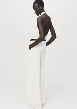 Blusa de cuello halter con diseño drapeado en el frente, confeccionada en tejido satinado de viscosa. Presenta un corte recto sin mangas y espalda abierta, ideal para eventos formales.