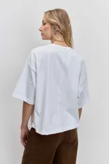 Remera blanca de corte oversize con cuello redondo y mangas cortas, presenta un pequeño bordado de cerezas en el pecho.