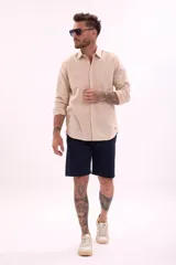 Camisa de manga larga color beige, con cuello clásico y botones frontales.