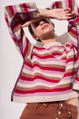 Sweater de lana con rayas horizontales en tonos rojo, rosa, beige y marrón. Presenta costuras decorativas en los laterales y puños en color violeta.