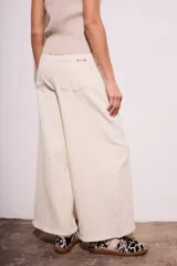 Pantalón jean de corte wide leg color crudo, tiro medio, confeccionado en algodón peinado con elastano.