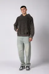 Buzo canguro de corte oversize en color gris con efecto lavado desgastado. Presenta diseño con recortes horizontales, capucha amplia y puños acanalados con etiqueta de marca en la manga.