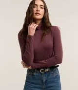 Suéter de cuello alto y manga larga, confeccionado en tejido de algodón con elastano. Presenta un diseño básico y ajustado al cuerpo.