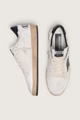 Zapatillas Golden Goose modelo Ball Star, confeccionadas en cuero con efecto desgastado. Diseño en color blanco con estrella lateral en negro, contrafuerte negro y suela de aspecto envejecido.