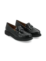 Mocasín de estilo clásico confeccionado en cuero charol negro, con detalle de hebilla metálica en el empeine y suela de plataforma de PVC con volumen marcado.