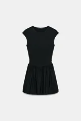 Vestido corto negro confeccionado en 100% algodón, de cuello redondo y mangas cortas. Presenta detalle de lazadas en los laterales de la cintura y falda con vuelo.