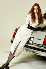 Falda midi color crema, de corte tubo, con cierre delantero, botón forrado, bolsillos laterales y tajo en la parte delantera.