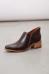 Botines de cuero negro con diseño moderno, silueta estilizada y punta fina. Cuentan con un corte en V en el lateral y tacón cuadrado de altura media.